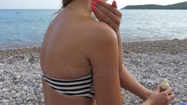 Kadın bikini korumak için Beach ve bulaşması vücut yağı ile oturur