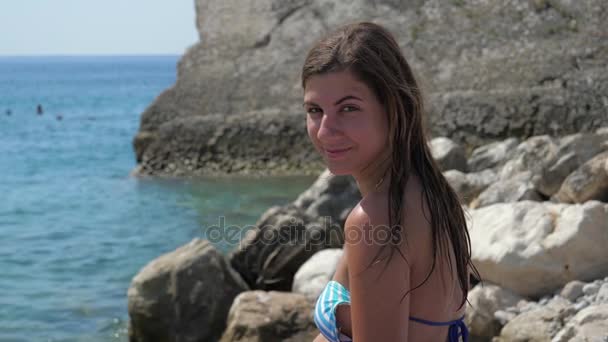 Close-up retrato de um feliz jovem morena mulher no biquíni sentado na praia — Vídeo de Stock