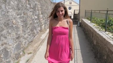 Genç gülümseyen kadın içinde pembe elbise gider üzerinde taş Street, ağır çekim, 4k