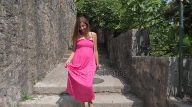 Esmer gülümseyen kadın içinde pembe elbise gider üzerinde Stone Street, ağır çekim, 4k