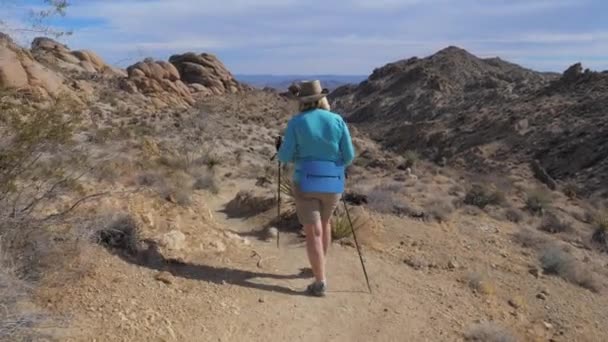 Toeristen oudere actieve vrouw lopen het voetpad In de Mojave-woestijn, achteraanzicht 4k — Stockvideo