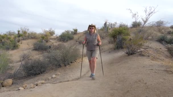 Actieve vrouw In Hat lopen het voetpad In de woestijn, een zand rond en een Cactus — Stockvideo