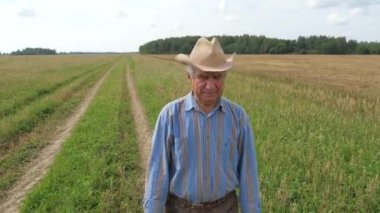 Yaşlı bir adam tarım ile ekili bir alan üzerinden bir patika boyunca yürüyüş