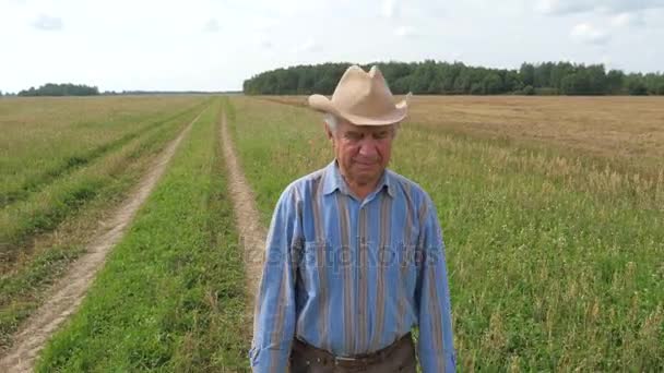 Un anciano está caminando a lo largo de un sendero a través de un campo sembrado de agricultura — Vídeo de stock