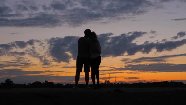 Silhouet romantisch paar, gekeken naar de dieprode zonsondergang, knuffelen elkaar. — Stockvideo