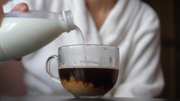 Närbild glas kaffe Mugg, i det Häll mjölk från burken och rör om med sked — Stockvideo