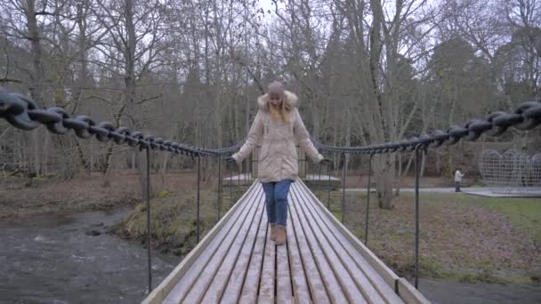 Mujer bonita caminando en puente colgante comienza a saltar sobre él y divertirse — Vídeo de stock