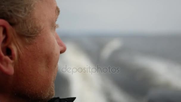 Primer plano vista lateral cara hombre navega rápidamente en un barco en el mar — Vídeo de stock