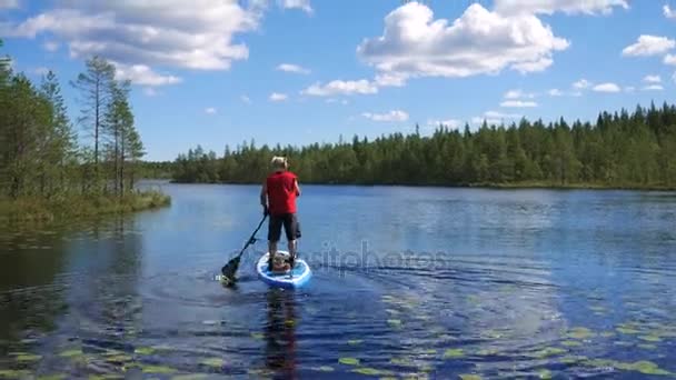 Muž plave na jezeře na nafukovací lodi stojící na ni, veslování s rukou vesla — Stock video