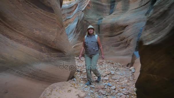 Mujer Senderismo en la garganta del río seco con rocas suaves y onduladas del cañón 4K — Vídeos de Stock