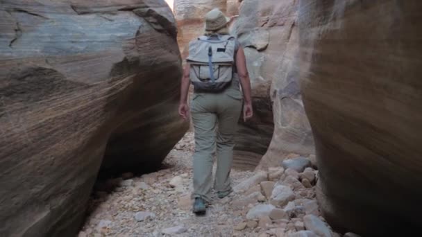 Mujer Senderismo en la garganta del río seco con rocas suaves y onduladas del cañón 4K — Vídeos de Stock