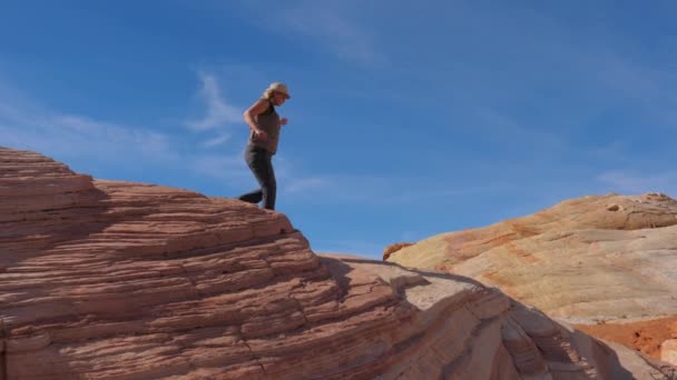 Turist kvinna vandring ned kullen Crest med färgglada Red Rocks Slow Motion 4k — Stockvideo