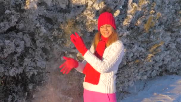 Mujer bonita arrojando nieve y de pie bajo la nieve, disfrutando del invierno al aire libre — Vídeos de Stock