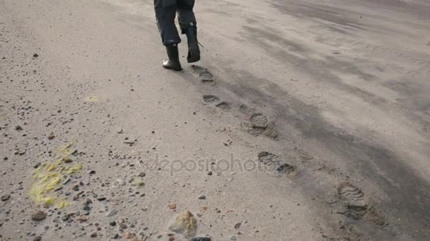 Чоловічий ноги в чоботях ходьба на піщаний пляж, залишивши позаду сліди 4 к — стокове відео