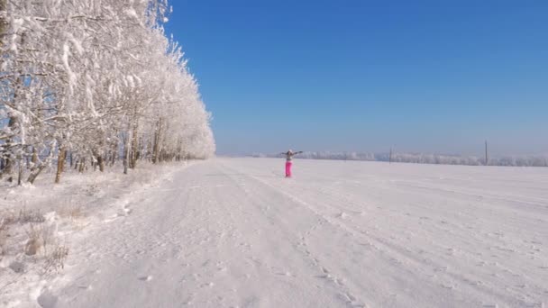 Mulher brincalhão correndo e girando no inverno na neve no campo, mãos no lado . — Vídeo de Stock