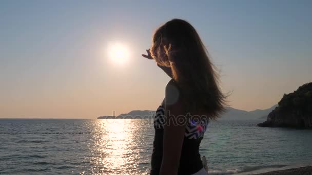 Placer Las manos femeninas atrapan el sol en el cielo de pie en la costa Mar de cámara lenta — Vídeo de stock