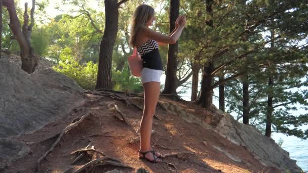 Jeune femme se tient dans un endroit pittoresque sur la côte de la mer, fait de la photo au téléphone — Video