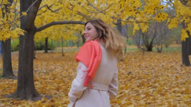 Dame in beigem Mantel und orangefarbenem Schal lehnt sich zurück und dreht sich um — Stockvideo