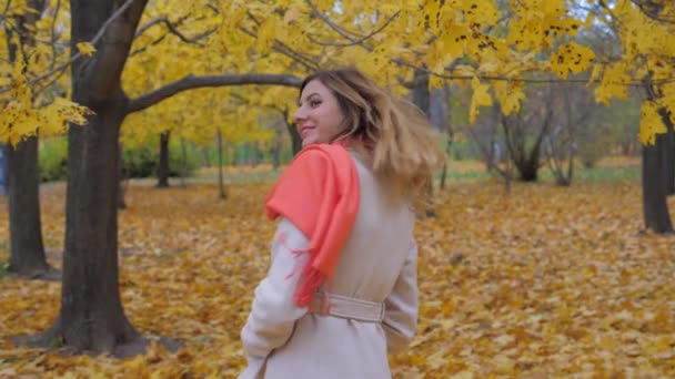 Dame en manteau beige et écharpe orange debout en arrière et fait demi-tour HD — Video