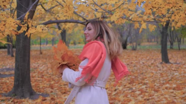 Dame dans un manteau beige debout en arrière et se retourne, tenant feuilles Bouquet — Video