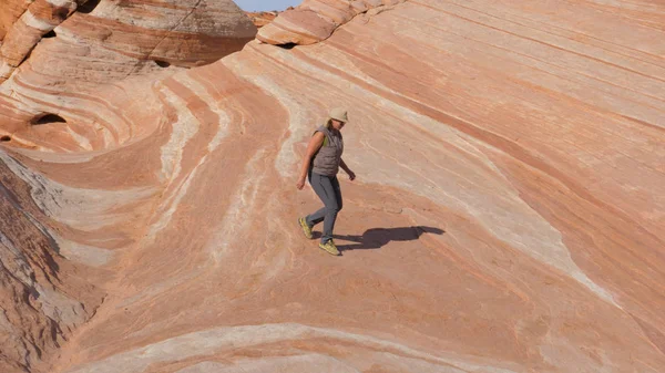 Turist kadın tepenin üst renkli taş kırmızı buzlu iner.