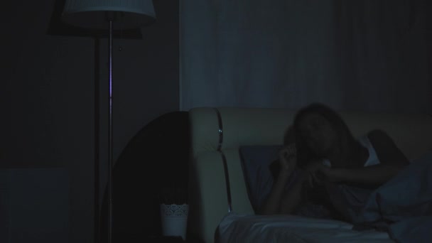 Mujer despierta por la noche enciende la lámpara toma y enciende el teléfono — Vídeos de Stock