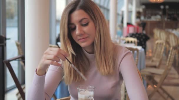 Woman In Cafe Drinking Coffee From A Straw Looks Dreamily Out Window At Street — Stock Video