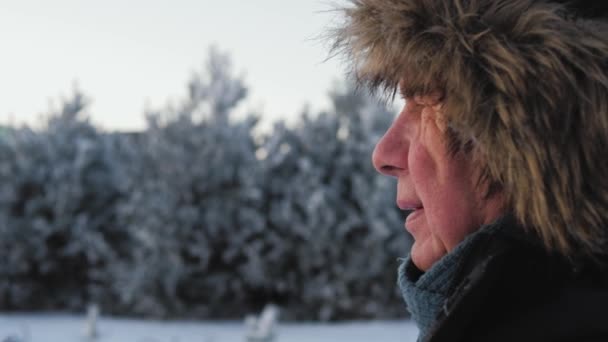 Portrét boční pohled starší muž s vrásky v bundě a kožešinovou čepici v zimě — Stock video