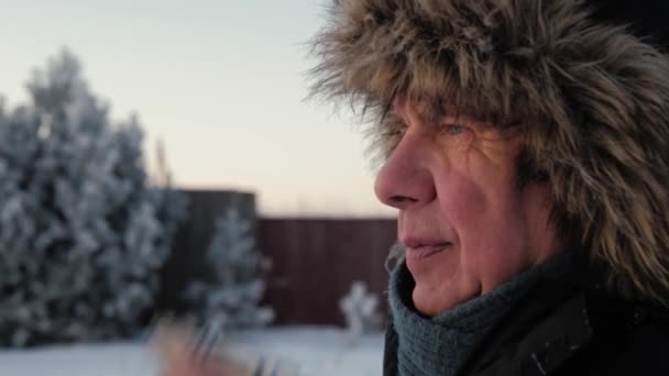 Hombre mayor con chaqueta y sombrero de piel en invierno se limpia la nariz con un pañuelo — Vídeos de Stock