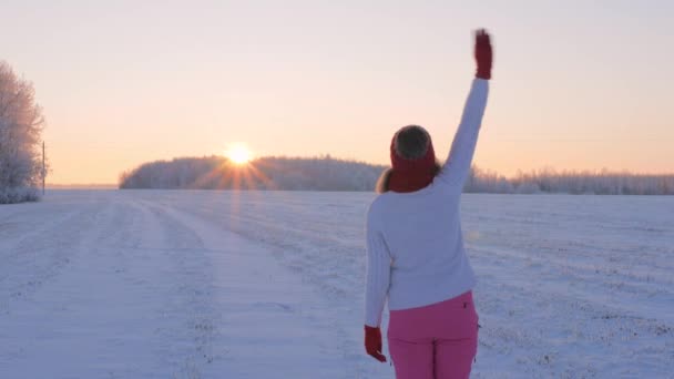Mujer viendo el atardecer saludando con la mano diciendo adiós al sol y al día en cámara lenta 4K — Vídeo de stock