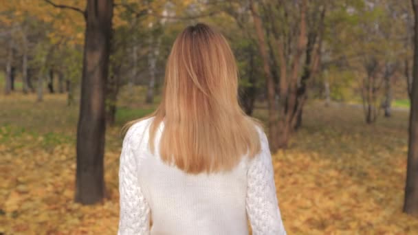 Motie weergave achterzijde vrouw wandelen, draait rond, vreugdevolle glimlachend In herfst Park — Stockvideo