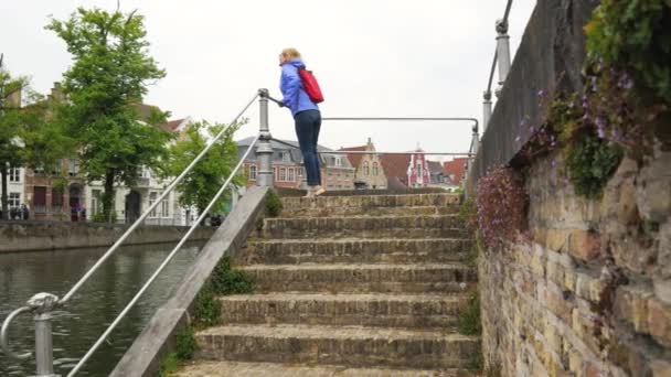 Жінка туристичних підходить до перила набережна і спуститися сходами для River — стокове відео