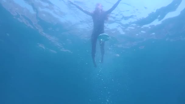 Vista submarina de mujer joven en bikini nada en el mar azul — Vídeos de Stock