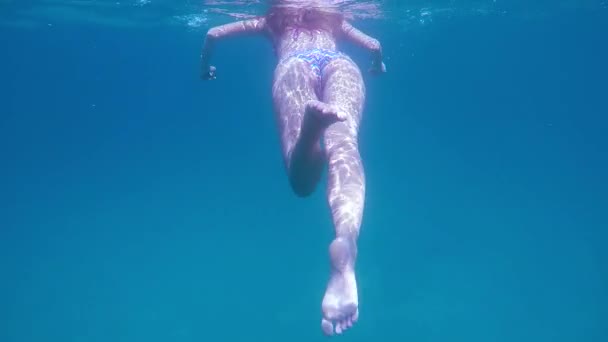 Unterwasser-Rückansicht einer jungen Frau im Bikini, die im blauen Meer treibt — Stockvideo