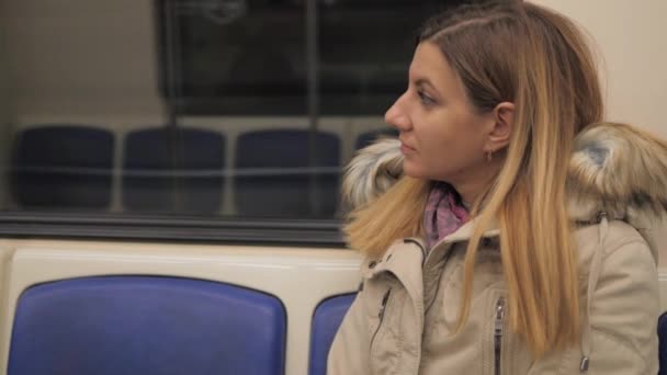 Close-up mulher vestida com jaqueta quente no metrô subterrâneo sentado na janela — Vídeo de Stock