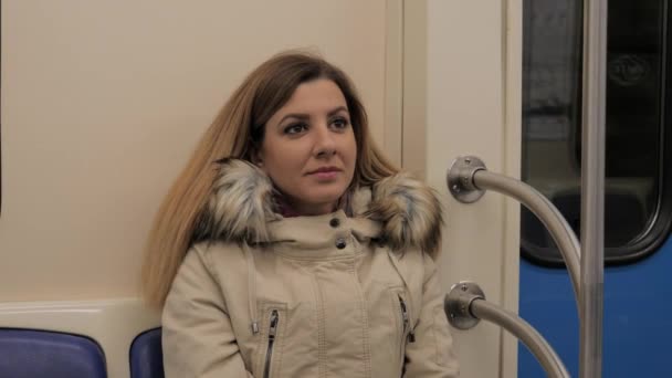 Närbild ung kaukasisk kvinna i varm jacka sitter i tunnelbanetåg — Stockvideo
