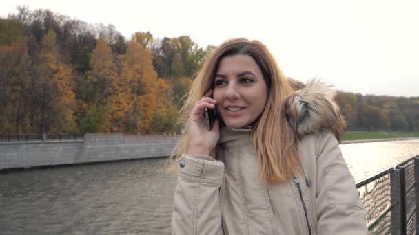 Vrouw praten over telefoon zeilen In de boot op de rivier in de buurt van kleurrijke herfst Park — Stockvideo