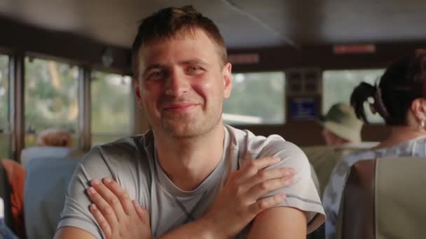 Портрет Красивый белый мужчина улыбается, глядя на камеру, сидящую в транспорте — стоковое видео