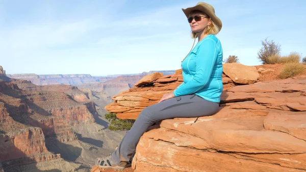 Touristin sitzt auf einem Felsen baumelt ihre Beine und bewundert die Aussicht Grand Canyon — Stockfoto