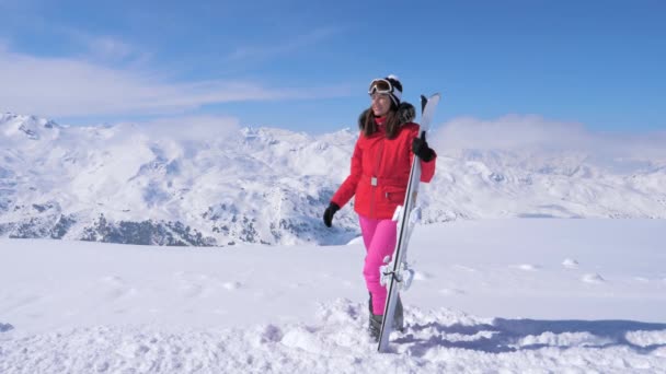 Kobieta trzyma Ski, noszenie maski narciarskie, stojąc na tle góry — Wideo stockowe