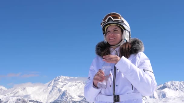 Donna sciatore bere acqua pulita da una bottiglia di plastica su uno sfondo di montagna — Video Stock