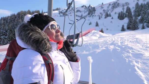 Mujer esquiadora sube una silla eleva una montaña en una estación de esquí — Vídeos de Stock