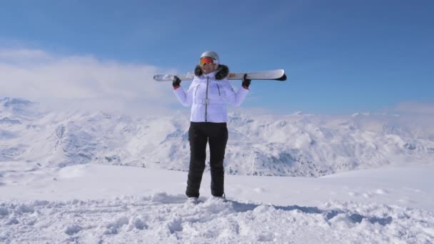 女子滑雪者站在山坡上, 举起滑雪和波浪4k — 图库视频影像