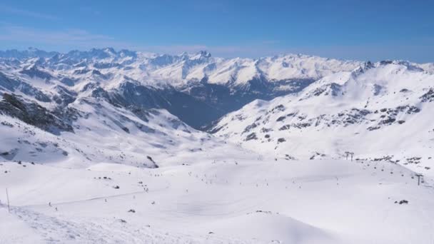 Μια καταπληκτική πανοραμική θέα τα χιονισμένα βουνά και σκιέρ στις πλαγιές — Αρχείο Βίντεο