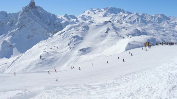Typisk solig dag i bergen på en skidort, många skidåkare i backen — Stockvideo