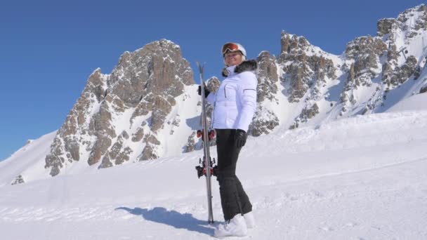 Donna sciatore sta dalla parte di una montagna che tiene gli sci — Video Stock