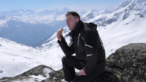 Mannen skidåkare äta en smörgås Lunch i skidorten berg — Stockvideo