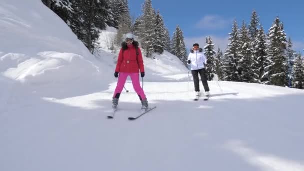 Двое лыжниц катаются на лыжах по склону рядом — стоковое видео