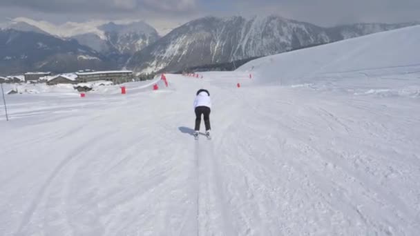 Skifahrerin beschleunigt Skifahren auf der Piste und hebt die Hände