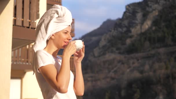 Γυναίκα πίνοντας ένα φλιτζάνι τσάι ή καφέ με τις ακτίνες του ήλιου στη βεράντα στα βουνά — Αρχείο Βίντεο